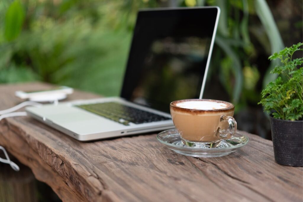 Laptop on wooden bench with coffee